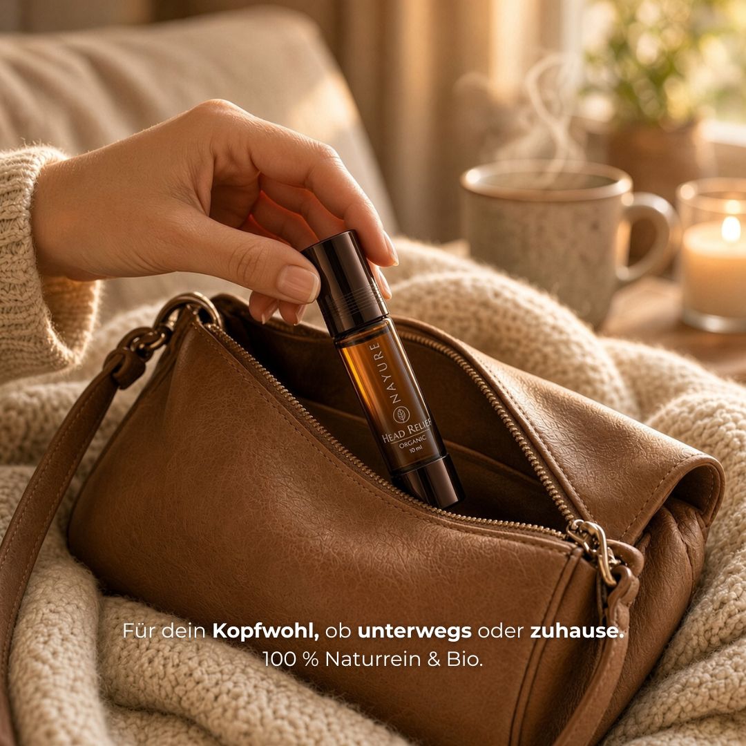 Hand zieht die NAYURE Head Relief Roll-on Flasche aus einer braunen Ledertasche, im Hintergrund eine Decke, eine dampfende Tasse und eine Kerze