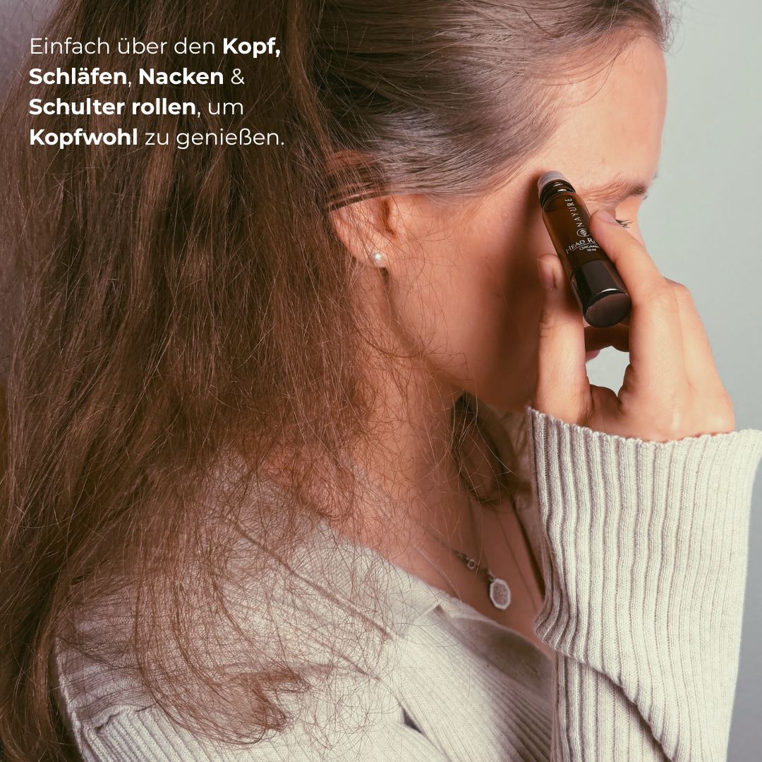 Frau rollt den NAYURE Head Relief Roll-on über die Schläfe, im Profil mit langen braunen Haaren und beigem Strickpullover