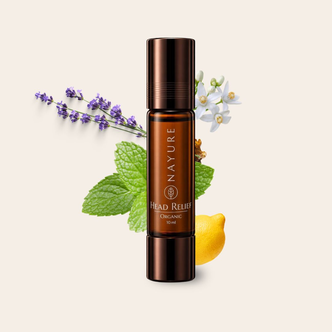 NAYURE Head Relief Organic 10 ml Roll-on in brauner Glasflasche mit dunklem Deckel vor Lavendel, Minzblättern, Neroliblüten und einer Zitrone auf cremefarbenem Hintergrund